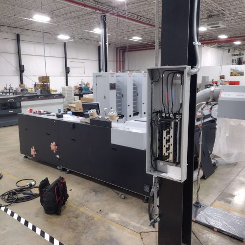 Lighting Installation on a large industrial machine stands in a warehouse, surrounded by equipment and tools
